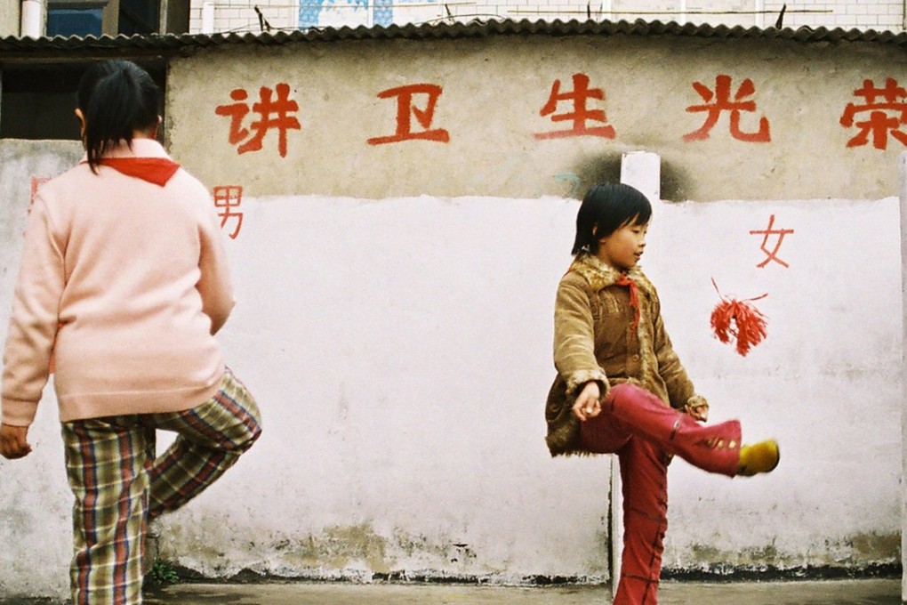 Chinese students kick a handmade shuttlecock in front of a washroom on a rooftop playground at a primary school for migrant workers' children in Wuhan on April 11, 2005. The school is built on the second floor of a farmers' market in the city, with the playground on the rooftop of the two-storey building. About 406 students study at the school. The Chinese characters read "It's glorious to maintain personal hygiene." Photo: Reuters