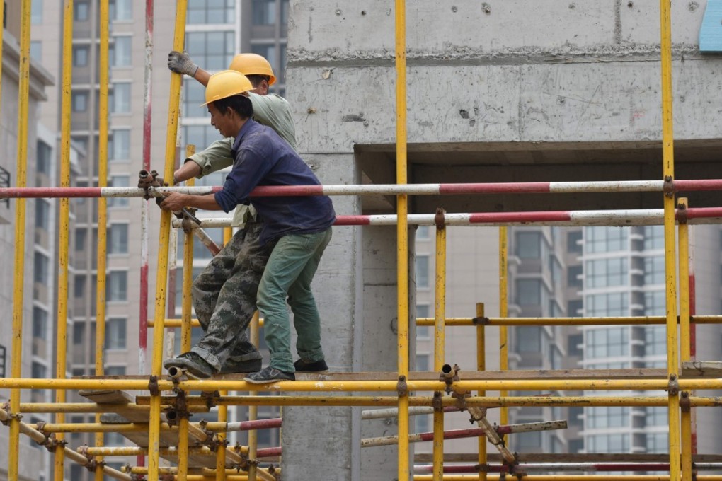 Construction workers erect scaffolding at a housing complex in Beijing on Tuesday. The IMF warned that China’s debt was on a “dangerous” path, but still raised its growth forecasts for the country. Photo: AFP