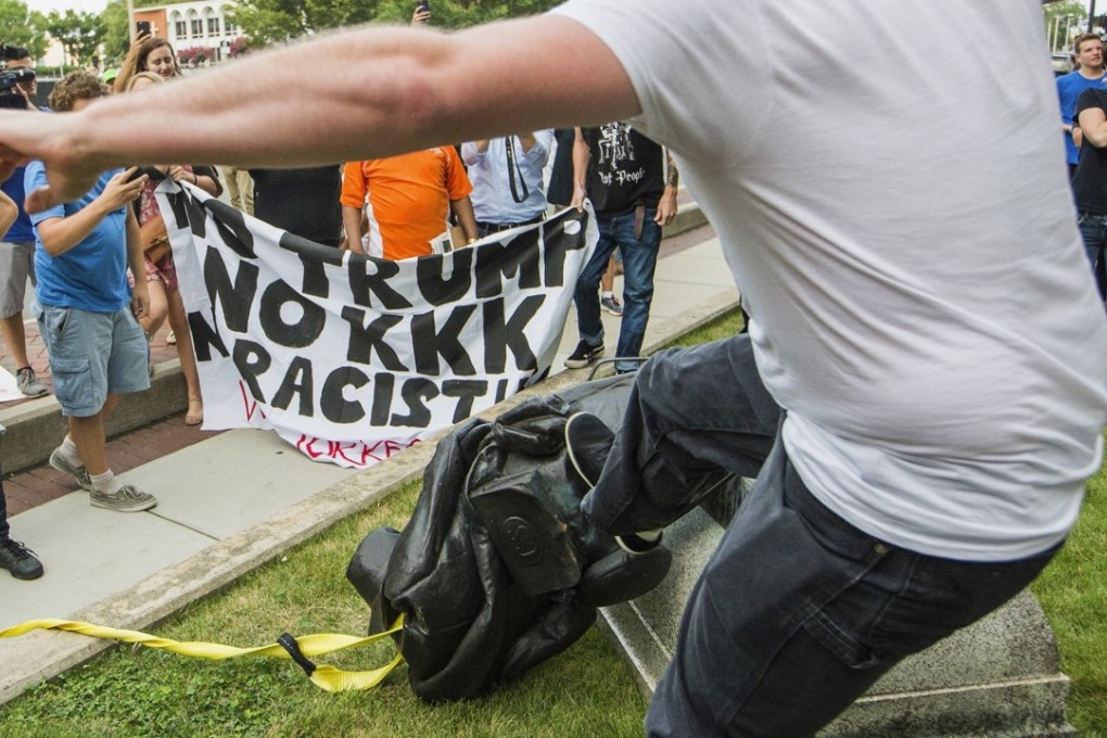 A protester kicks the toppled statue of a Confederate soldier after it was pulled down in Durham, North Carolina, on Monday. Photo: AP
