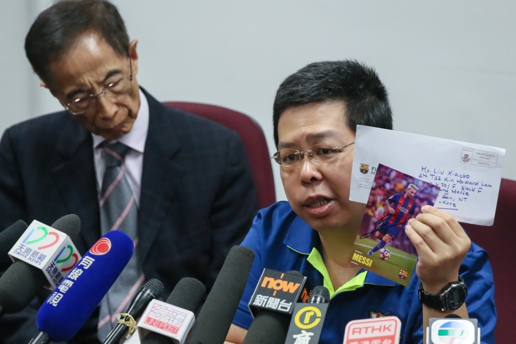 Howard Lam holds up a Lionel Messi postcard at a press conference in Hong Kong, as former Democratic Party chief Martin Lee Chu-ming looks on, on August 11. Lam claimed he was tortured as he planned to give the signed postcard from the Barcelona football star to Liu Xia, the widow of Liu Xiaobo. Photo: EPA/Handout