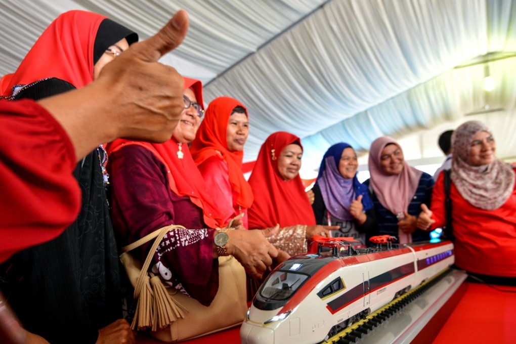 Women pose with a model train during the ground breaking ceremony for the East Coast Rail Link project in Malaysia, on August 9. The scheme is one of many being developed under China’s “Belt and Road Initiative”. Photo: Xinhua