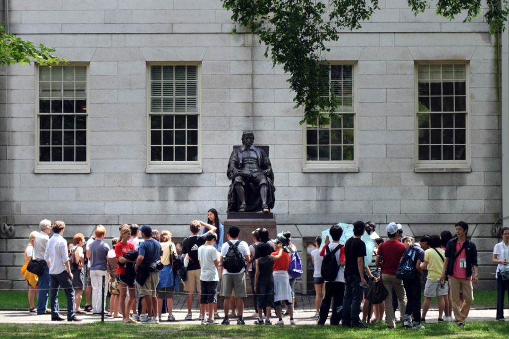People touring Harvard Yard stop by the John Harvard statue just off Harvard Square in Cambridge, Massachusetts. Photo: AFP
