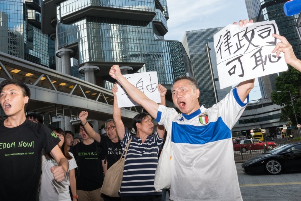 Supporters of student activists Joshua Wong, Nathan Law and Alex Chow hold up signs reading “Shame on the Department of Justice” (right) and “Freedom Stolen” as the three leave Hong Kong’s High Court in prison vans, on August 17. Photo: EPA