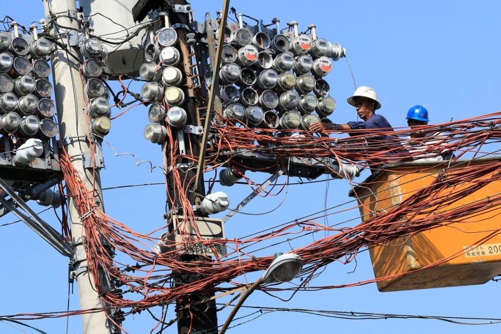 Filipino workers repair power metres in Manila. Photo: Reuters