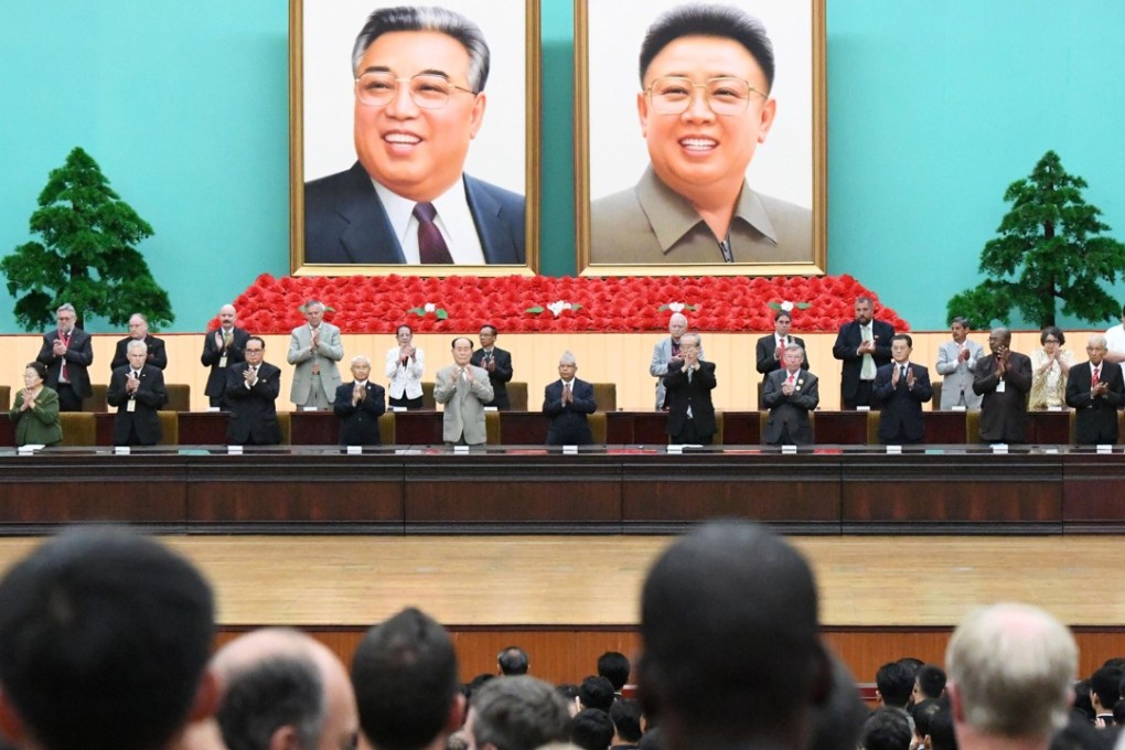 Giant portraits of founding leader Kim Il-jung (left) and his son Kim Jong-il form the backdrop for a gathering to sing the praises of North Korea’s ruling family, in Pyongyang on August 15. Photo: Kyodo
