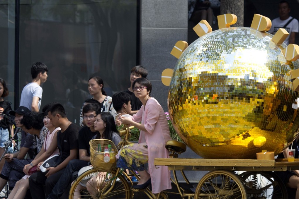 A woman sits on a tricycle painted gold and used as a marketing gimmick in Beijing on August 8, 2017. China's demand for the precious metal rose 10 per cent to 545 tonnes during the first six months of 2017. Photo: AP