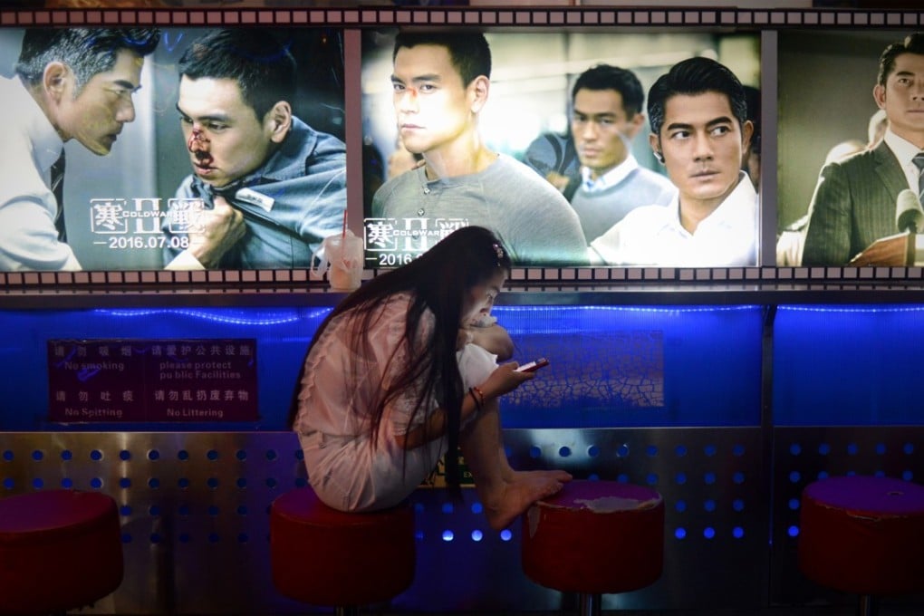 A woman looks at her mobile phone at the entrance of a cinema in Beijing on August 30, 2016. Photo: AFP PHOTO