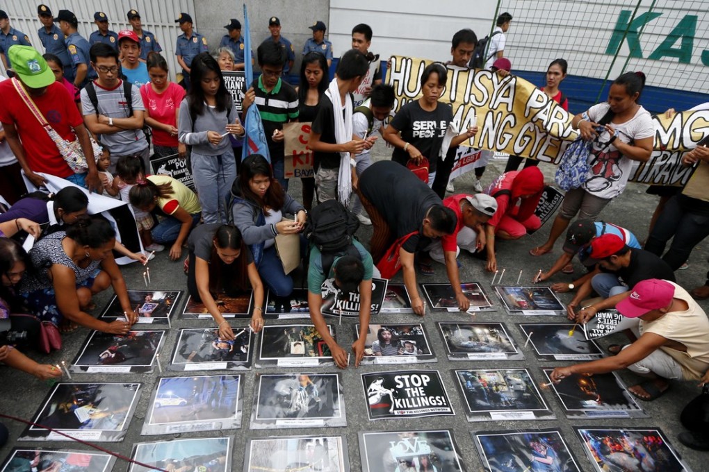 Protesters arrange candles and photographs in tribute to the alleged victims of extrajudicial killings. Photo: AP