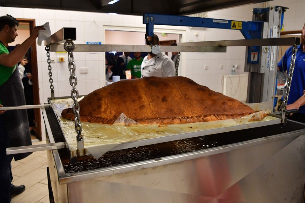 Muslim Aid staff and volunteers winch the world’s largest samosa out of the fryer at the East London Mosque in Tuesday. Photo: AFP