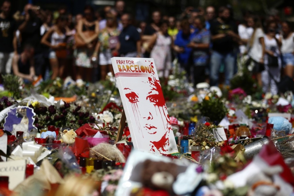 People stand next to candles and flowers placed on the ground after Thursday's terror attack that left many killed and wounded in Barcelona, Spain. Photo: AP