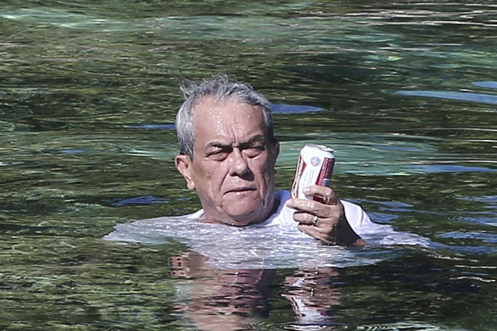 Marshall Islands Foreign Minister Tony de Brum cools off and relaxes with beer while he sits on a rock in Majuro Atoll in 2015. Photo: AP