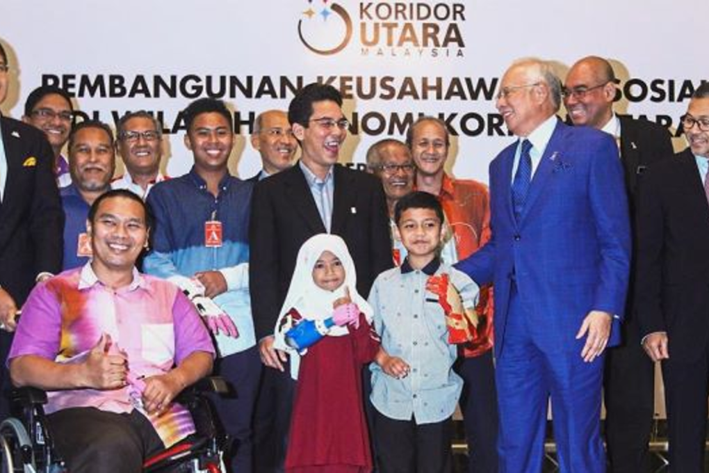 Najib sharing a light moment with Pak Su as Fathul (centre), Redza (second from right) and other prosthetic limb recipients look on in Putrajaya. Photo: The Star