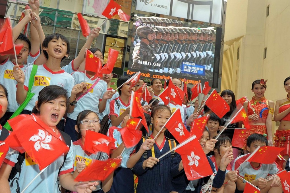 This handout photo from Hong Kong PR company Wasabi Creation shows mainland Chinese children cheering with Hong Kong and Chinese flags as they watch the broadcast of the military parade in Beijing, at the World Trade Centre building in Hong Kong on October 1, 2009. Photo: AFP