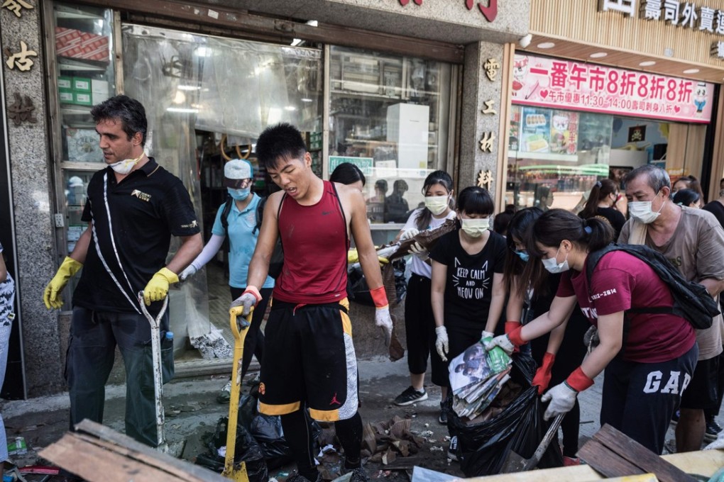Local residents clean debris and rubbish on a street in the aftermath of Typhoon Hato in Macau. Photo: AFP Photo