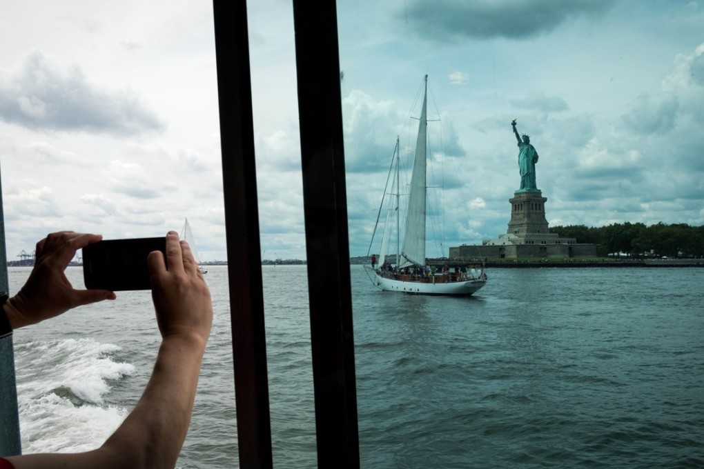 A man takes a photograph as he rides a ferry toward Liberty Island and the Statue of Liberty. File photo: AFP