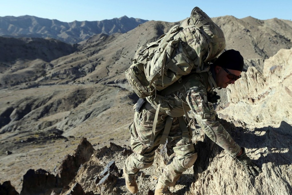 A US soldier climbs a hill with a heavy rucksack in Afghanistan. Photo: Reuters