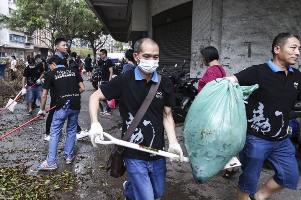 Macau residents clear the streets, covered with piles of rubbish and debris, after the city was hit by two storms in the past week. Photo: Nora Tam