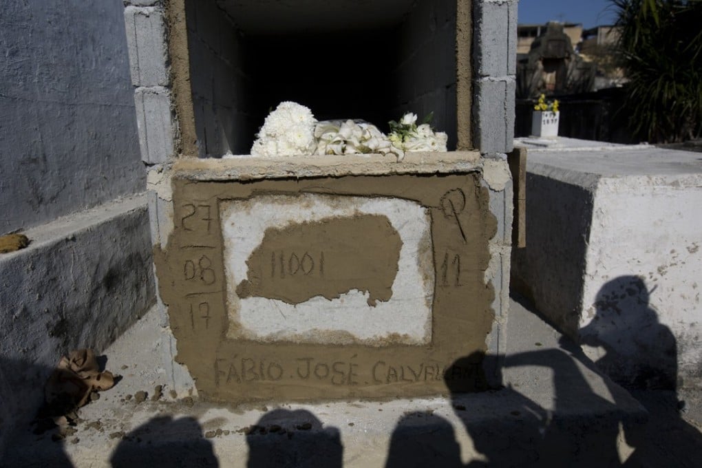 People's shadows are cast on the tomb of Sergeant Fabio Cavalcante. Photo: AP