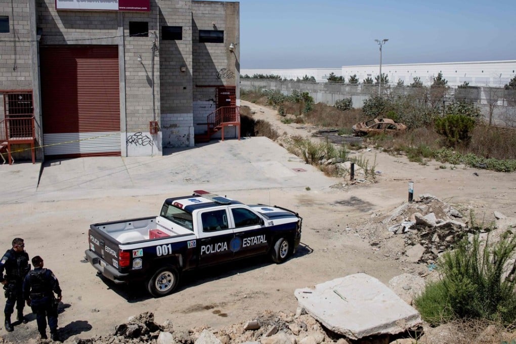 Mexican police stand guard at a warehouse where the entrance of a tunnel used to smuggle Chinese nationals into the US was found in Tijuana on Sunday. Photo: AFP