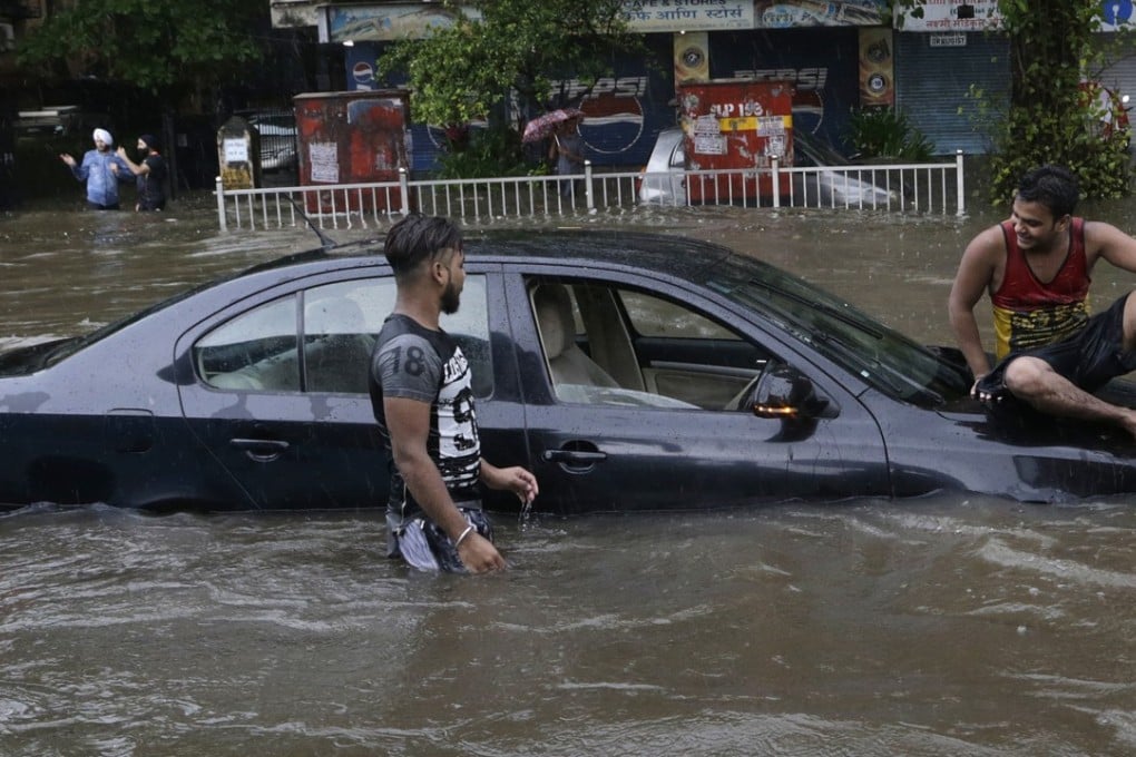 A man sits on a car that got stuck in a waterlogged street following heavy rains in Mumbai, India. Photo: AP