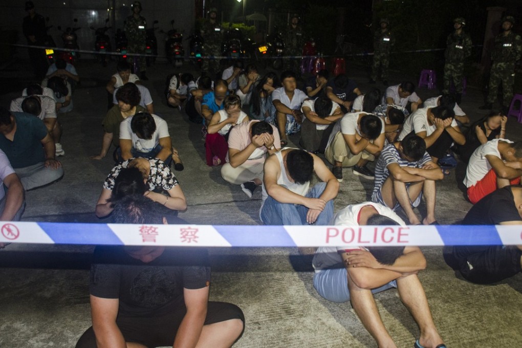Armed police officers stand guard as dozens of suspects are rounded up in Beihai on Wednesday morning. More than 1,200 people were arrested in coordinated raids on 300 properties in the coastal city in southwestern China. Photo: CNS