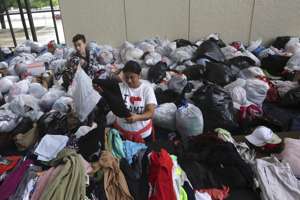 Volunteers Brenda Tcoc, right, and Hugo Wilson help sort bags of donated clothes for victims of flooding after a shelter opened at the Lakewood Church in Houston on Tuesday. Photo: AP