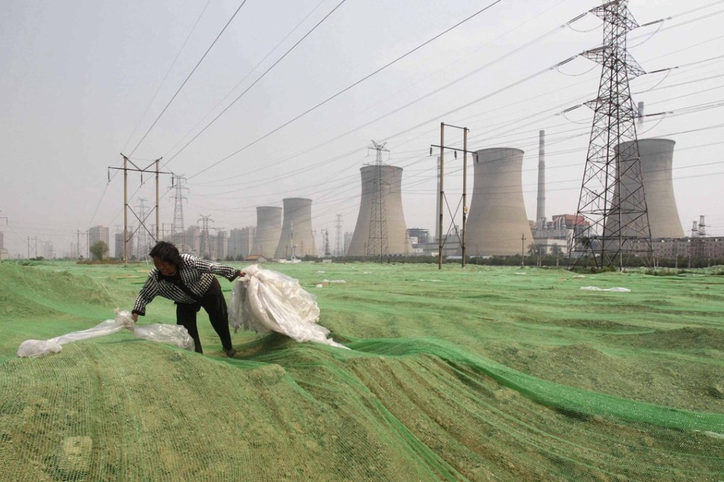 A labourer collects plastic bags on a dust screen covering construction waste near a power plant in Zhengzhou, Henan. China plans to have total nuclear capacity of 58 gigawatts by the end of the decade. Photo: Reuters