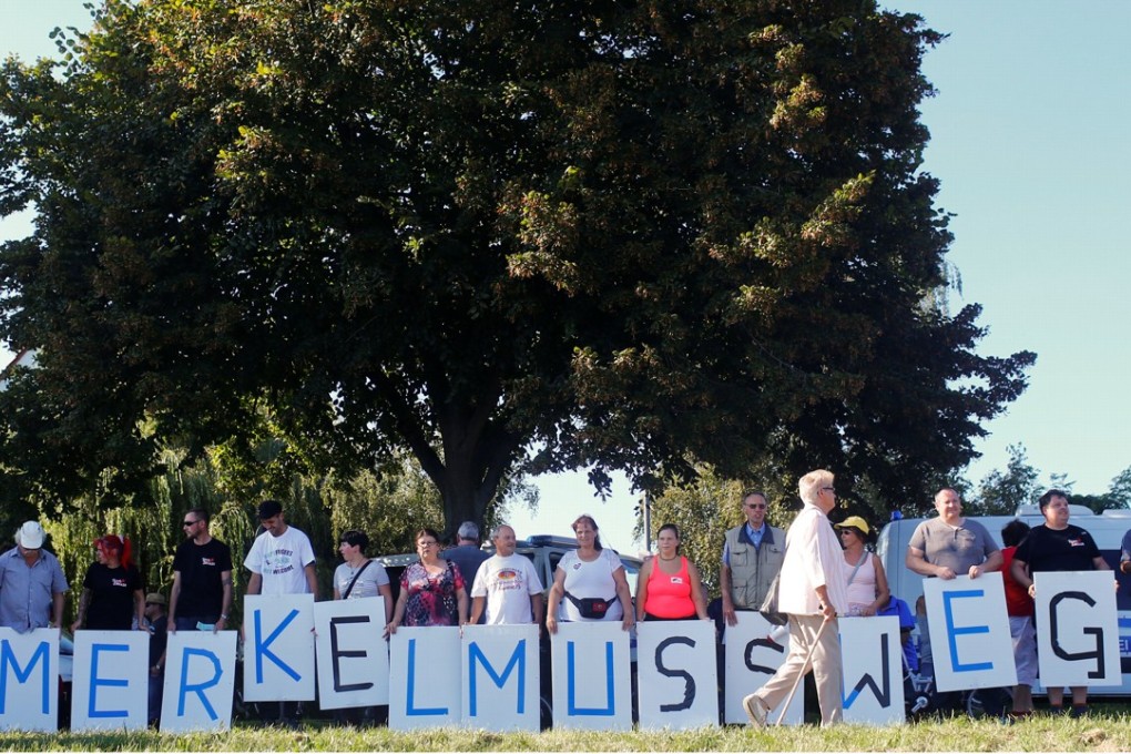 AfD Party supporters holding signs that together say “Merkel must go”. Photo: Reuters