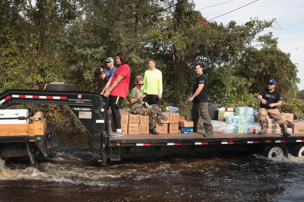 Volunteers distribute food, water and pet food to flood victims from the back of a lorry trailer. Photo: AFP