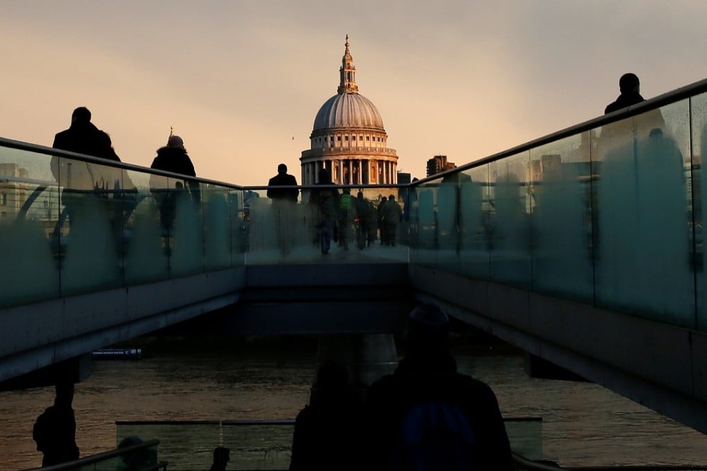 City workers walk towards St Paul's Cathedral as they cross the Millennium footbridge at sunrise in central London in this file photo. Photo: Reuters