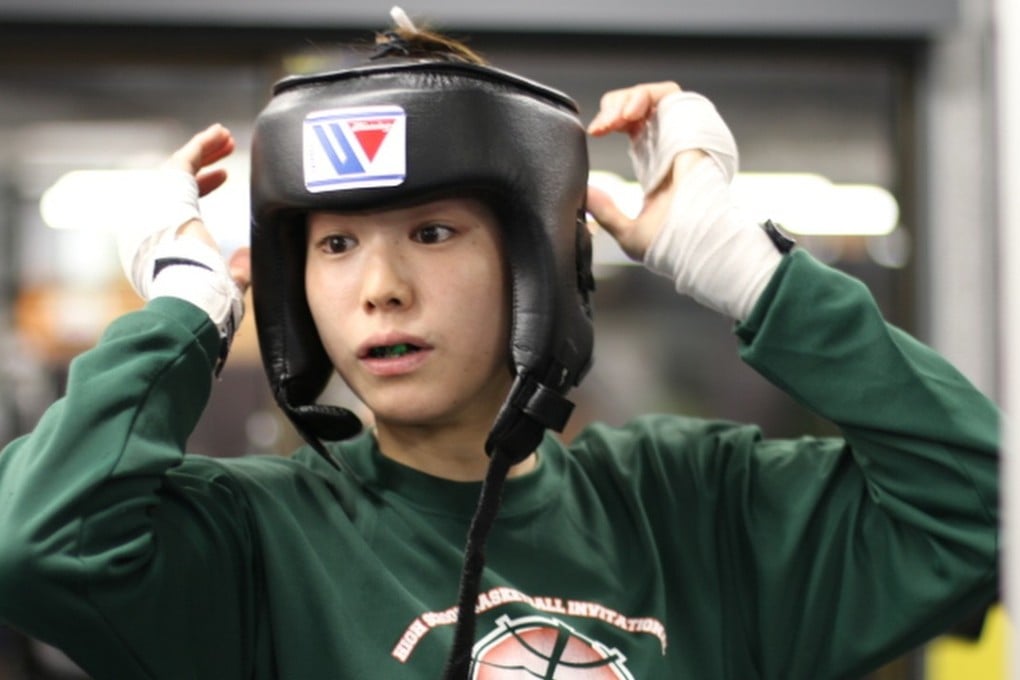 Japanese boxer Ayumi Goto puts on her head gear before her sparring session in Tokyo. Photo: Unus Alladin