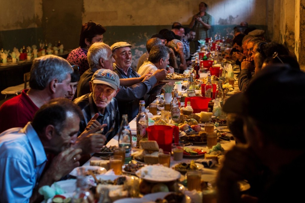 Family and friends gather at a supra, or feast table, to celebrate the first birthday of a family’s first child. Photo: Alamy