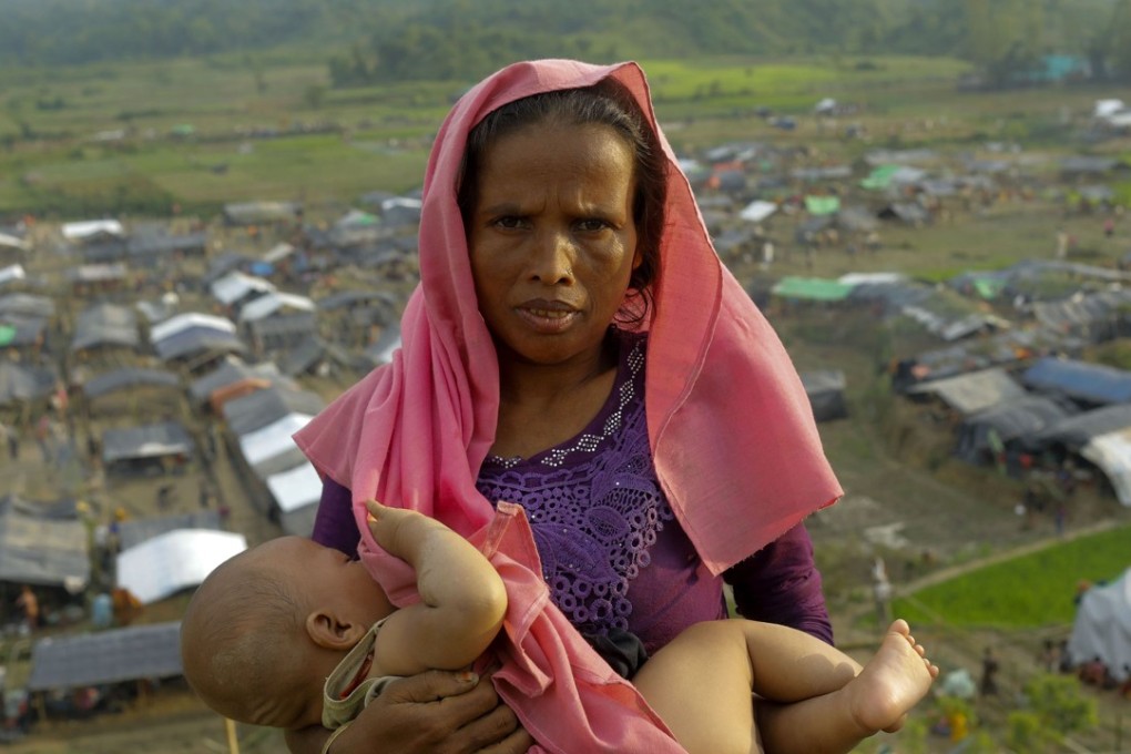 A Rohingya Muslim woman from Myanmar carrying a baby after arriving at a new camp for refugees in Unchiprang near the Bangladeshi border town of Teknaf. Photo: AFP