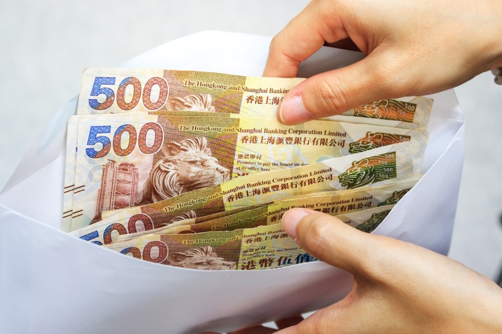 Hong Kong dollar bank notes money in white envelope and business woman hand. Hong Kong dollar bills in envelope. Female hand with money in cash with selective focus and soft focus. exchange concept Photo: Shutterstock