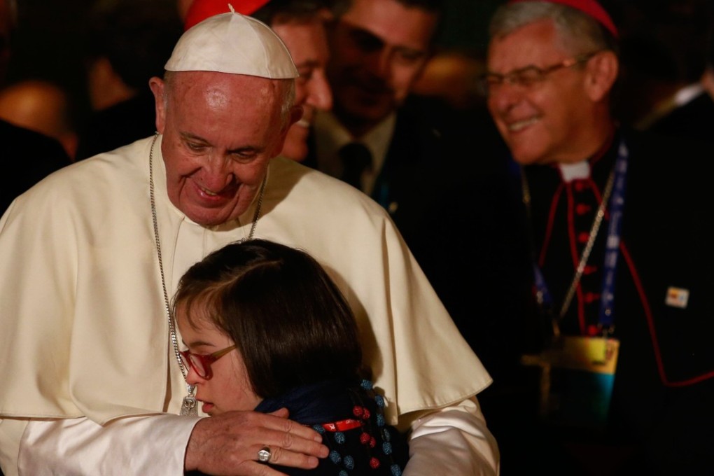 Pope Francis hugs a girl during a ceremony at the Nunciature in Bogota. Photo: AFP