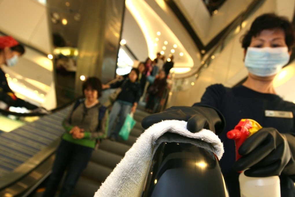 A worker cleans an escalator in Hong Kong with a bleach-based solution. Photo: SCMP Picture