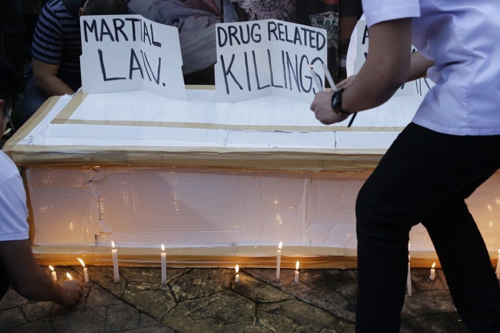 Seminarians light candles beside a mock coffin as they participate in a rally in Manila protesting against drug-related killings and martial law. Photo: AP