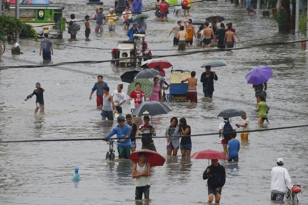 Residents in Manila wade through floodwater after a tropical depression caused mass flooding in the city and nearby areas. Photo: AP