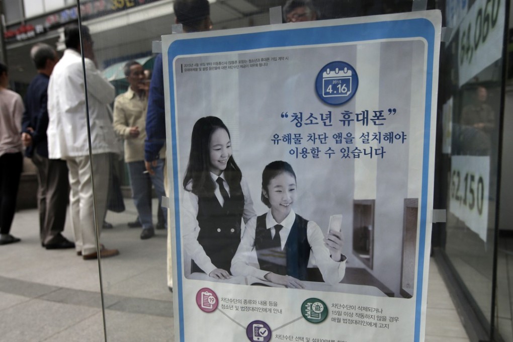 A promotional banner of mobile apps that block harmful content is posted on the door at a mobile store in Seoul, South Korea in 2015. The banner reads: ‘Young smartphone users, you must install apps that block harmful content.’ File photo: AP