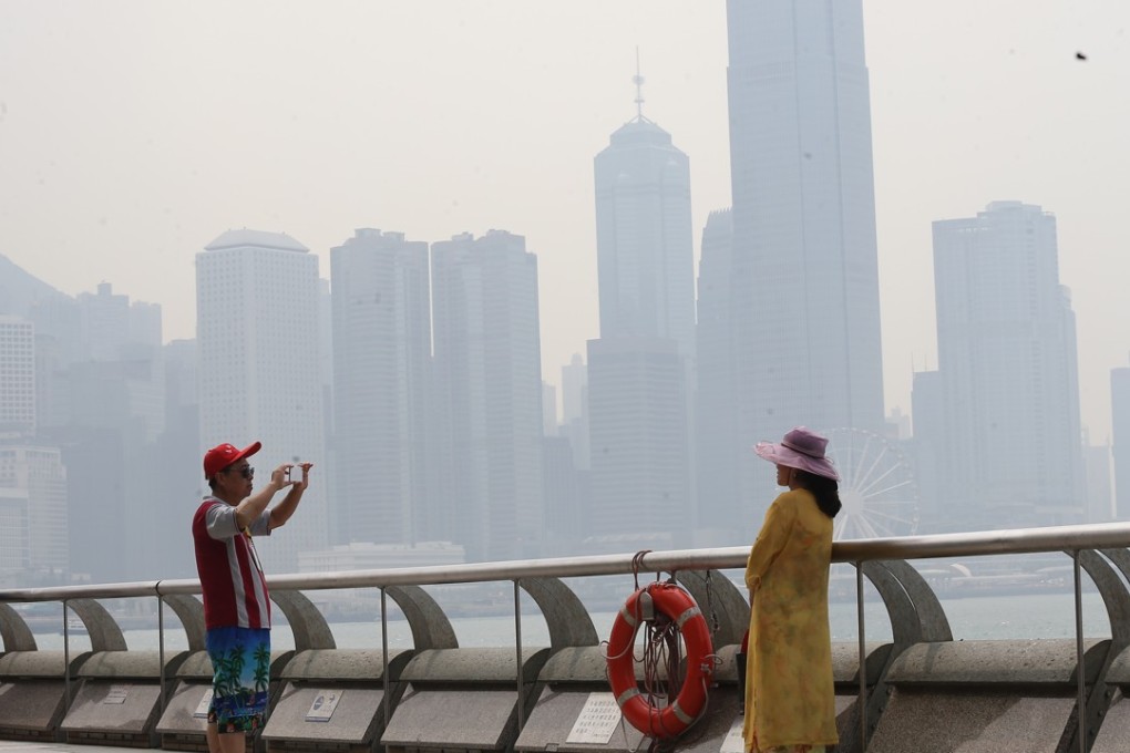 Tourists take pictures in Tsim Sha Tsui amid hazy conditions. Photo: Dickson Lee