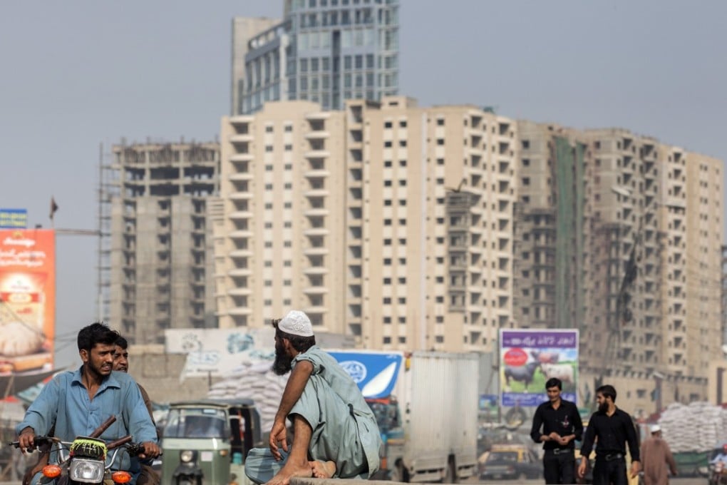 Men chat in front of buildings in Karachi, Pakistan, in August. The appeal of Karachi, home to some 15 million people, two large seaports and Pakistan's financial infrastructure, is set to rise as China pumps in more than US$50 billion to boost infrastructure and transport links across the nation. Photo: Bloomberg