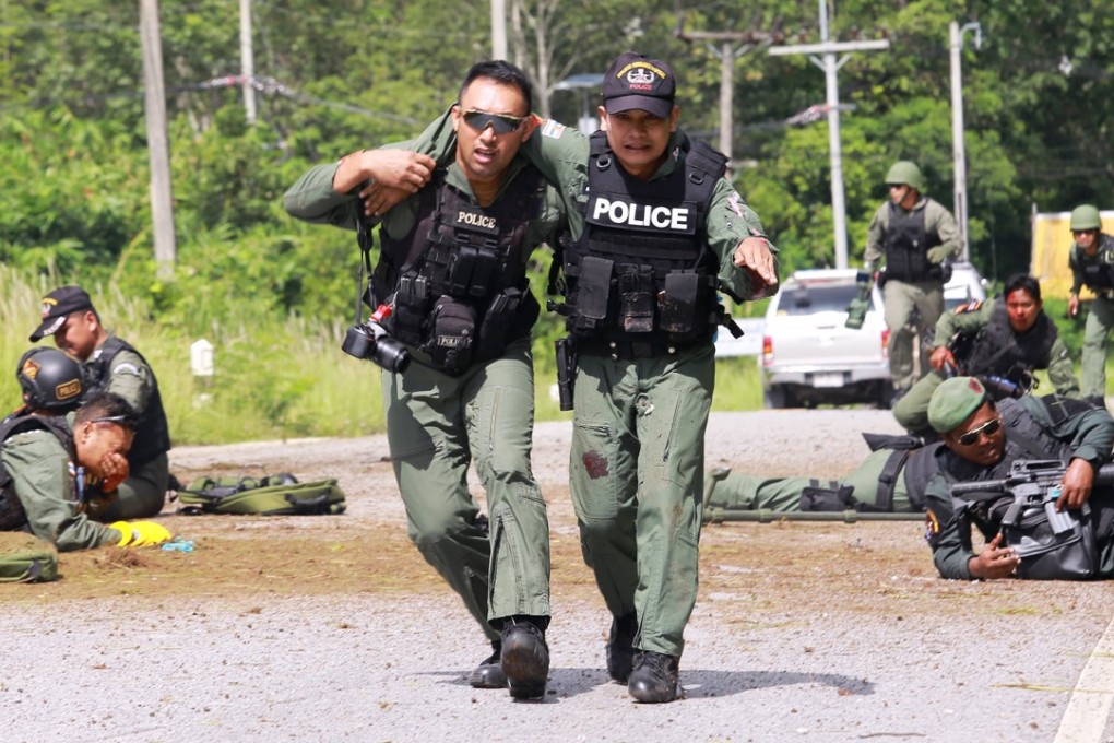 Thai police officers help injured comrades from the scene after an ambush bomb attack. Photo: EPA