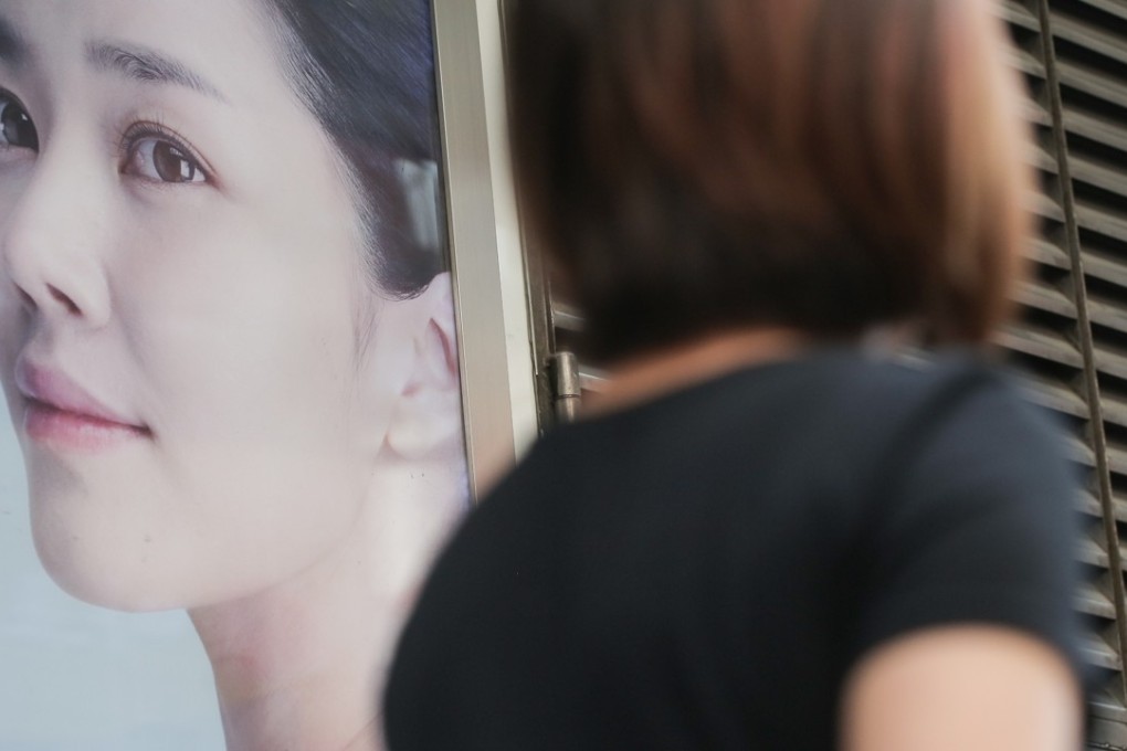 Women walk past an advertisement of beauty centre on the street in Causeway Bay. Consumer Council has urged the government to regulate beauty treatment requiring medical procedures. Photo: Paul Yeung