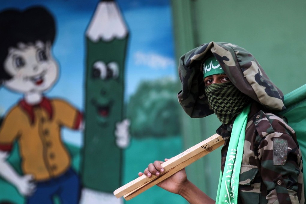 A masked youth cadet of the Ezzedine al-Qassam Brigades, the armed wing of the Palestinian Islamist Hamas movement, carries the movement's flag at a march in the southern Gaza Strip city of Khan Yunis. Photo: AFP
