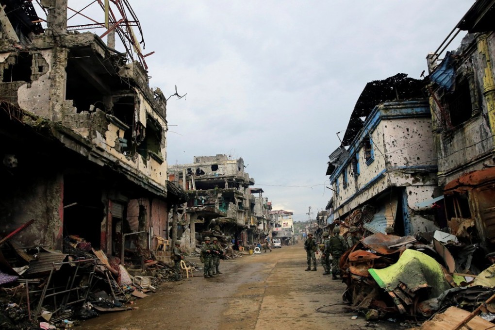 Government soldiers stand guard in front of damaged buildings and houses in Marawi City. Photo: Reuters