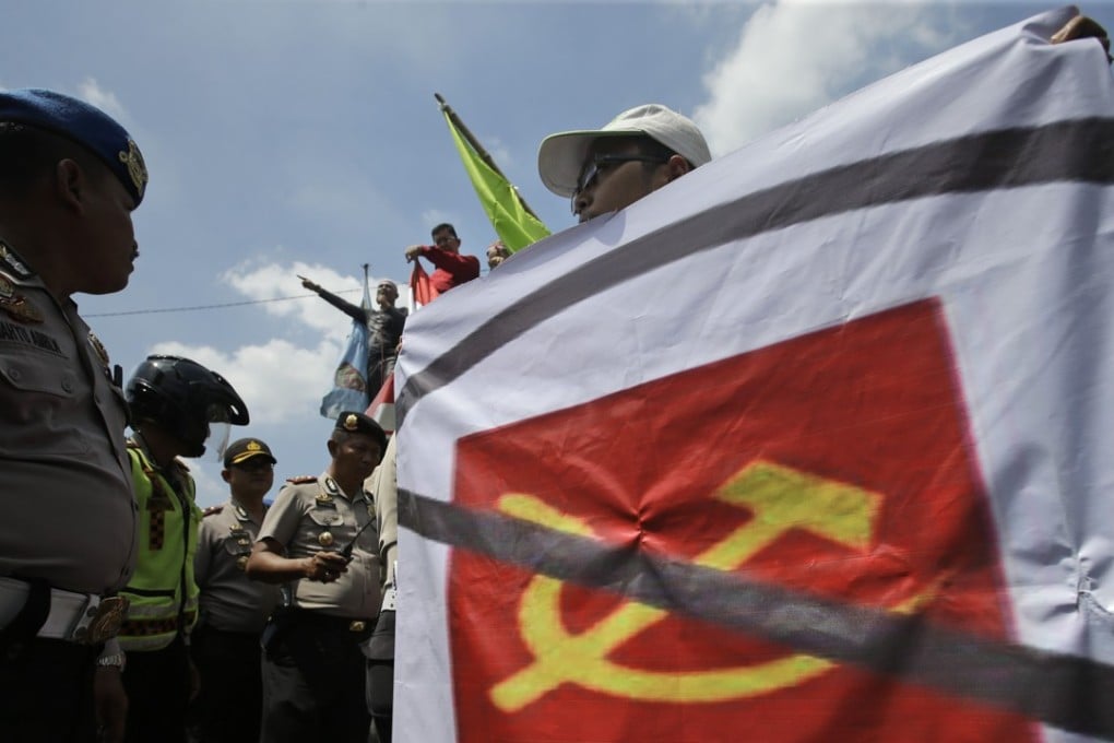 A man carries a banner of defaced communist symbol during a protest in Jakarta last year against the discussion of anti-communist massacres in 1965. Photo: AP