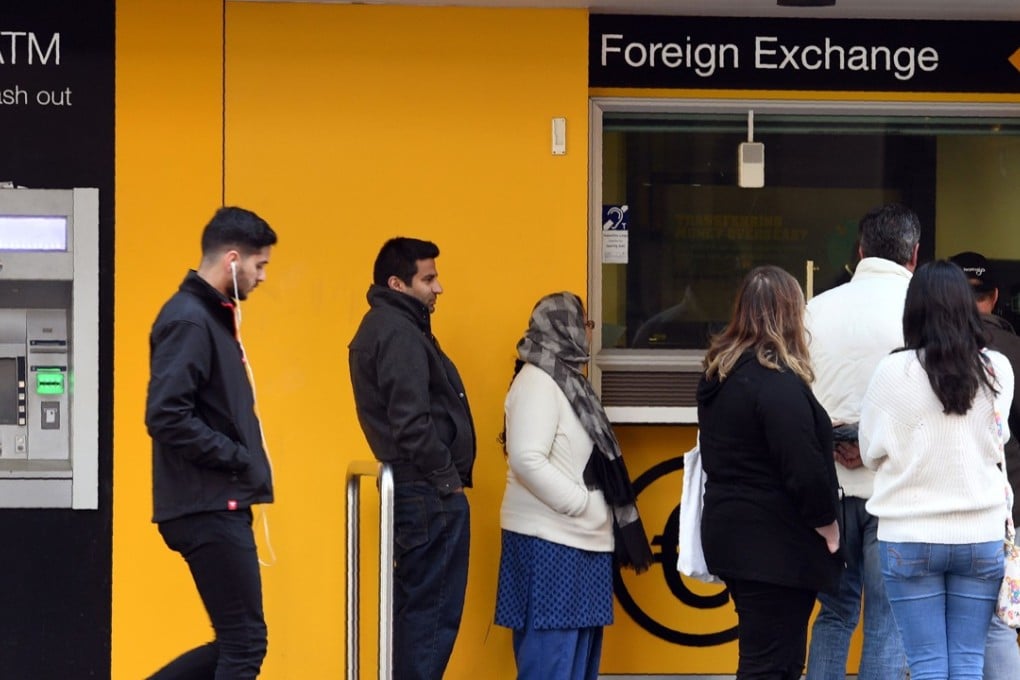 People queue outside a foreign exchange booth at a branch of the Commonwealth Bank of Australia (CBA) in Sydney. Photo: AFP