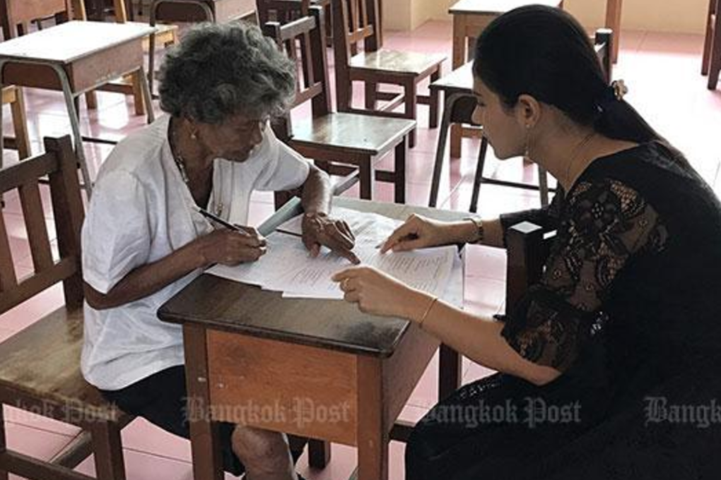 Prapasri Paowal, head of the the Non-Formal and Informal Education Office in tambon Kuan Pring of Trang, gives exam instructions to her oldest student, Grandma Khlong Faikhao. Photo: Methee Muangkaew/Bangkok Post