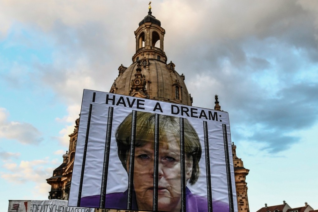 A protester waves a placard depicting Angela Merkel in prison at a rally for the German right-wing populist party Alternative for Germany (AfD) in Dresden on Monday. Photo: EPA