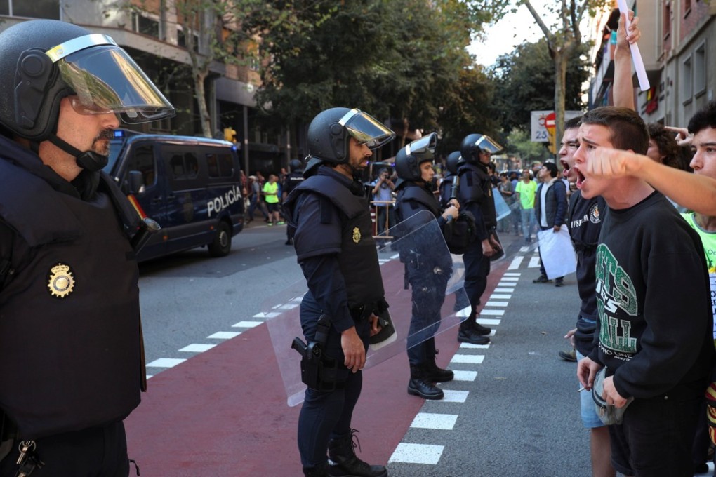 Protesters shout in front of a line of Spanish national police. Photo: Reuters